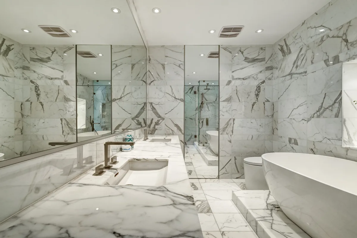 Book-matched Calacatta marble bathroom with a freestanding tub in a modern luxury residence