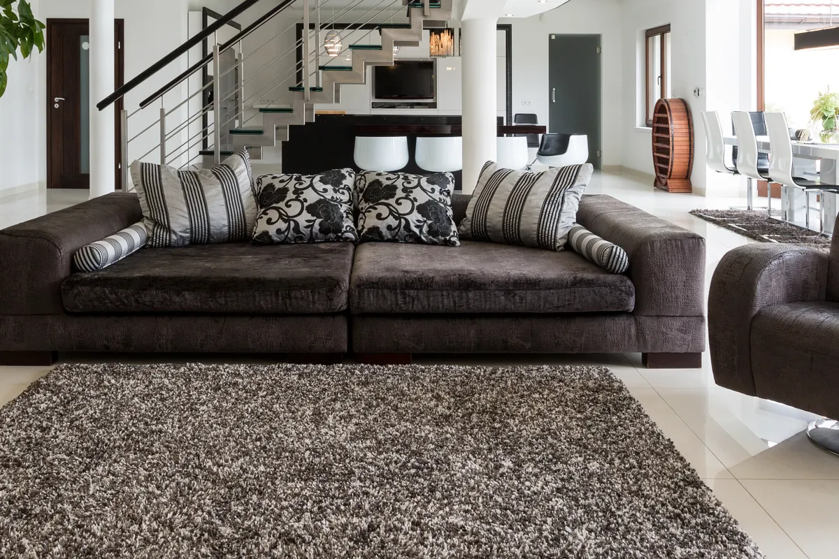 Bright, spacious open-plan luxury living room with marble floors and floor-to-ceiling glass
