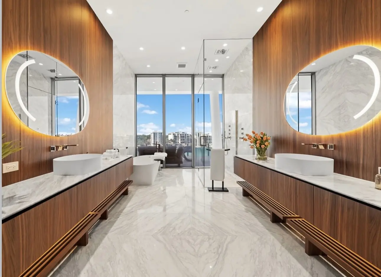 Vita Grove Isle penthouse primary bathroom with book-matched marble, freestanding tub and dual mirrors