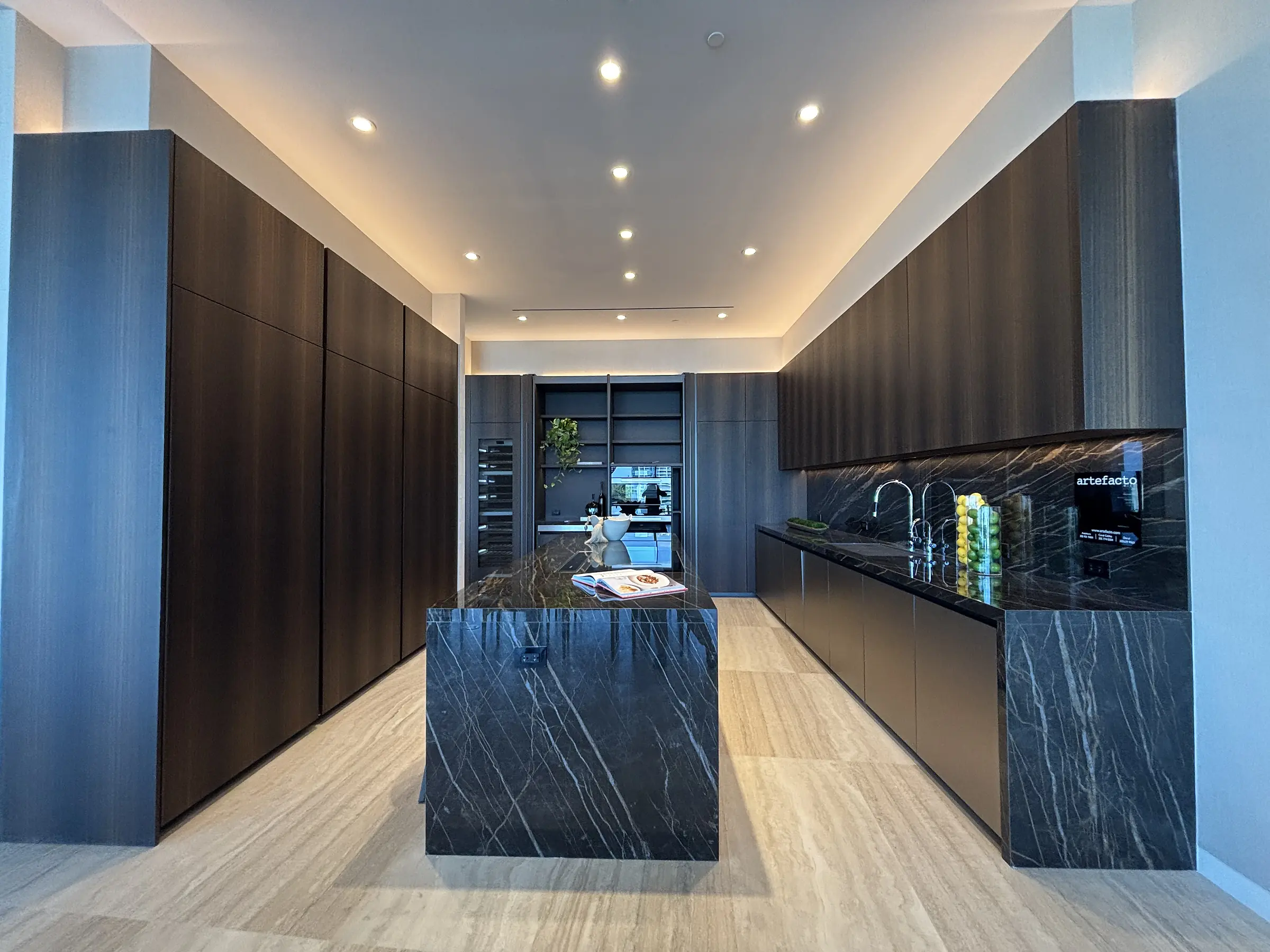 Vita Grove Isle penthouse kitchen with walnut millwork and marble island under ambient lighting