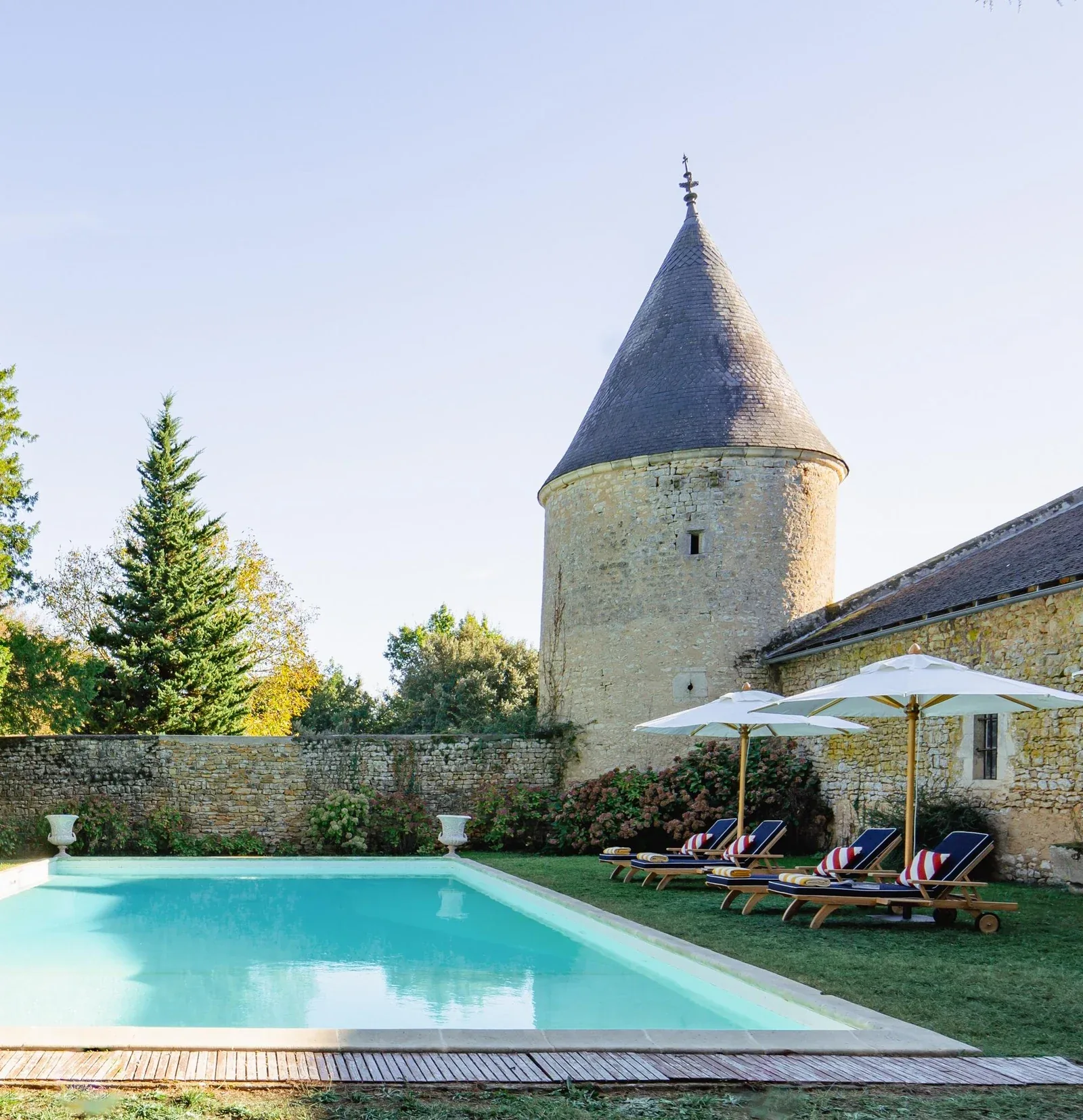 Private château estate swimming pool beside a medieval stone tower and walled garden