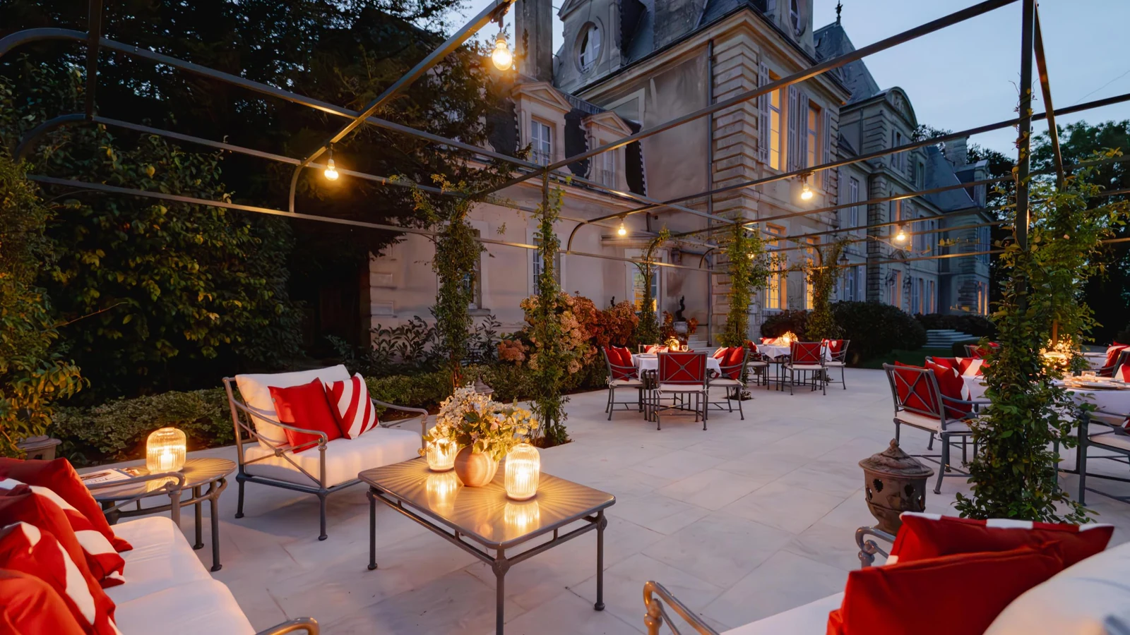 Private château estate terrace laid for evening dining under festoon lighting