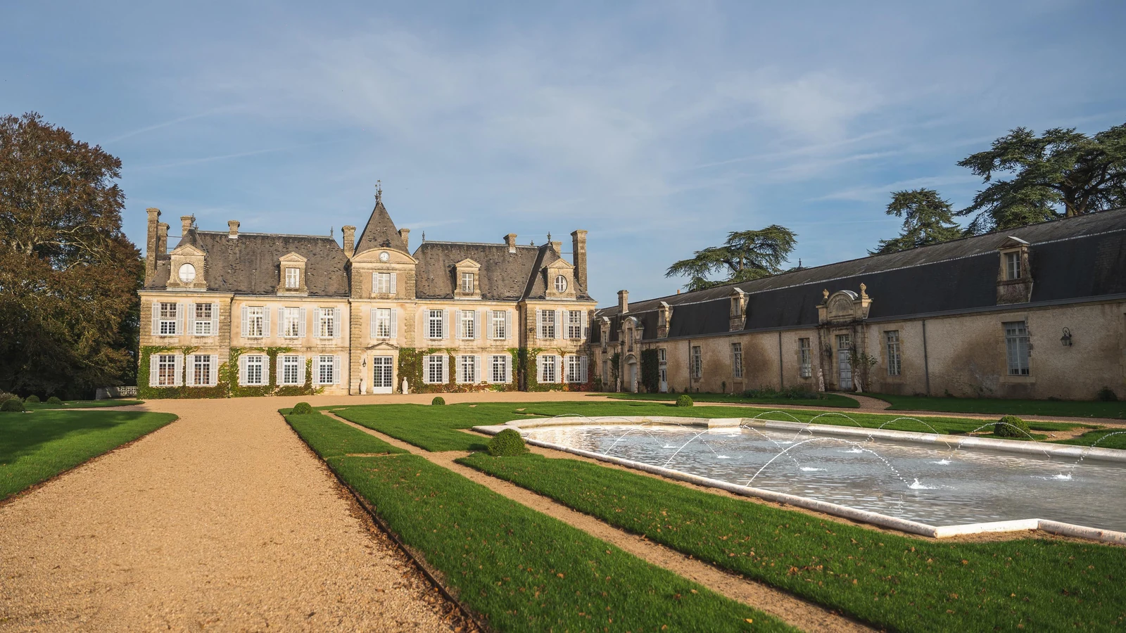 Private château estate main façade with reflecting fountain and formal gravel forecourt