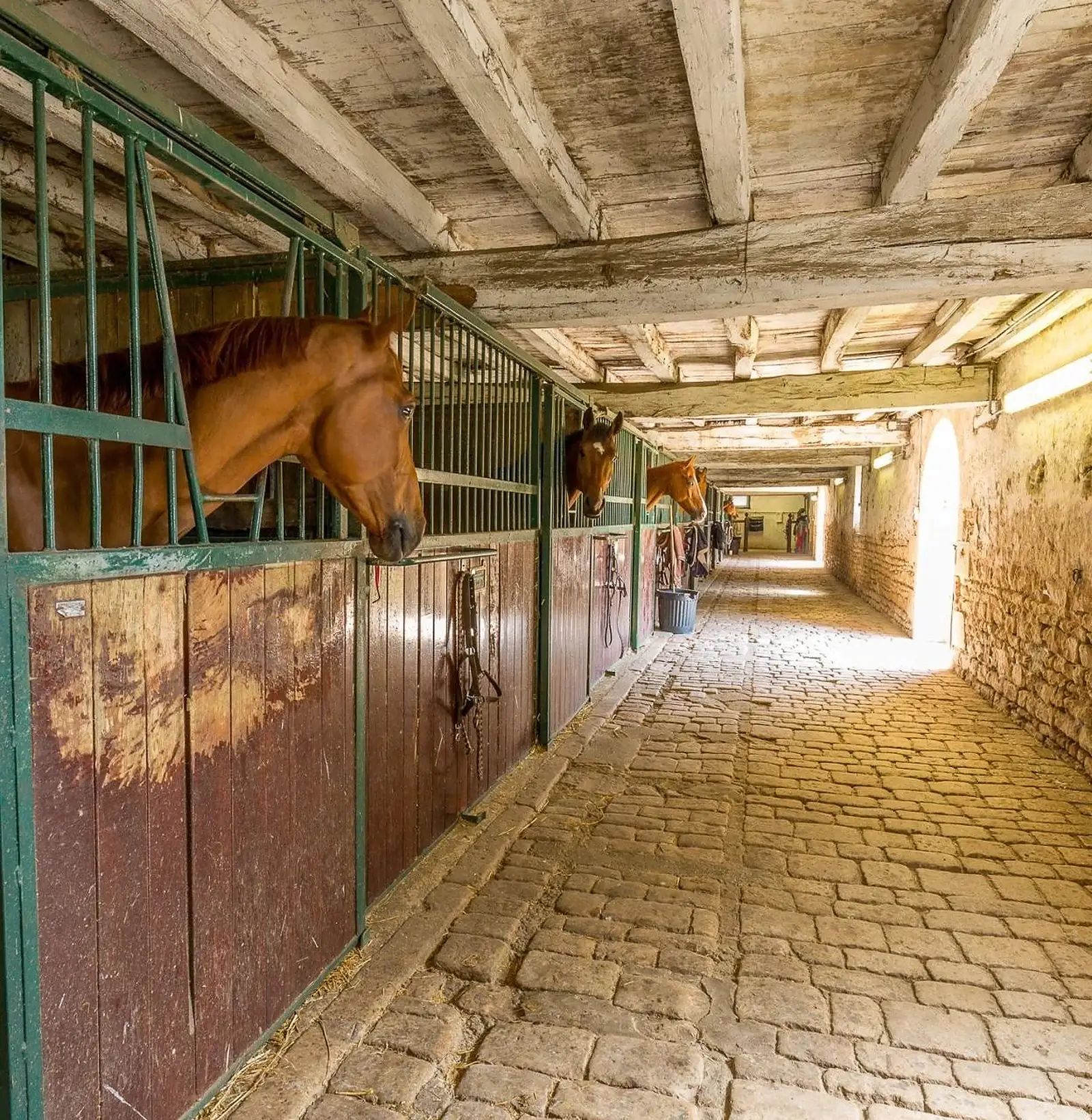 Private château estate stable block interior with timber boxes and cobbled aisle