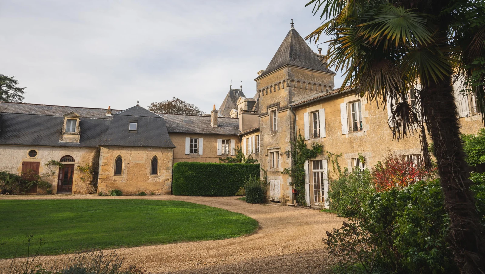Private château estate logis courtyard with gothic chapel window and lawned garden