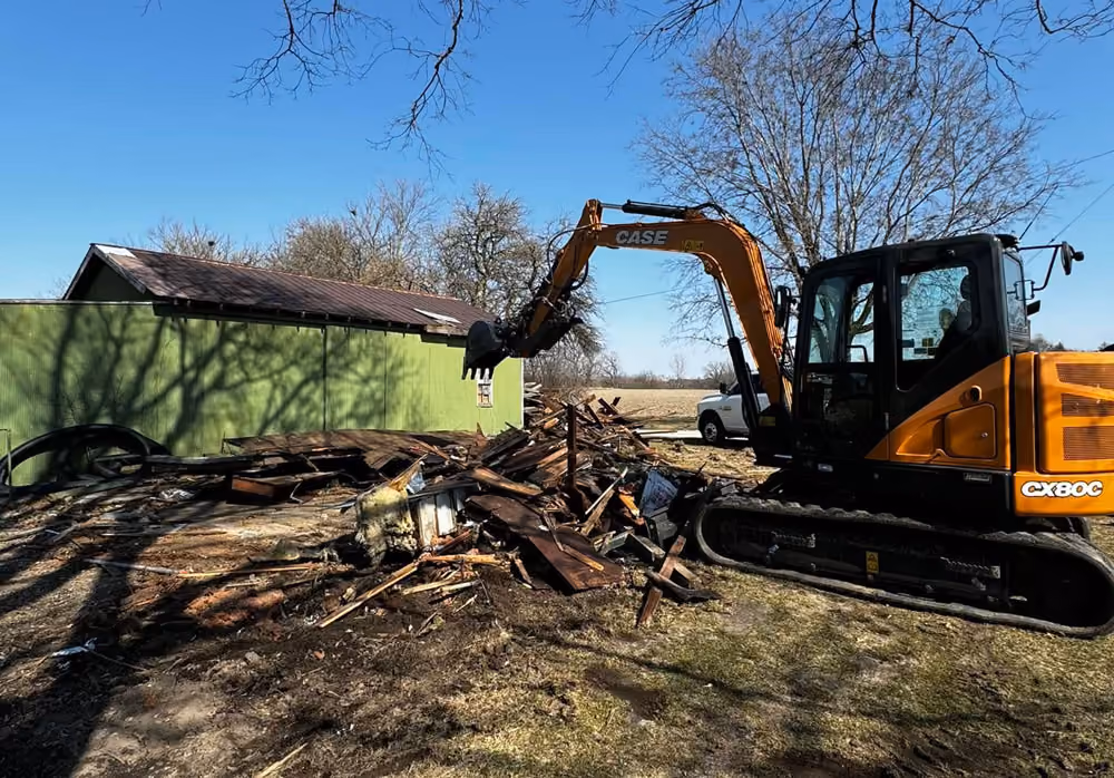 Excavator tearing down a structure and clearing debris