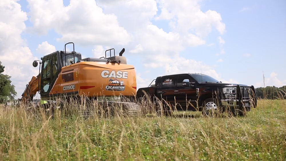 CASE excavator and pickup truck parked in a grassy field