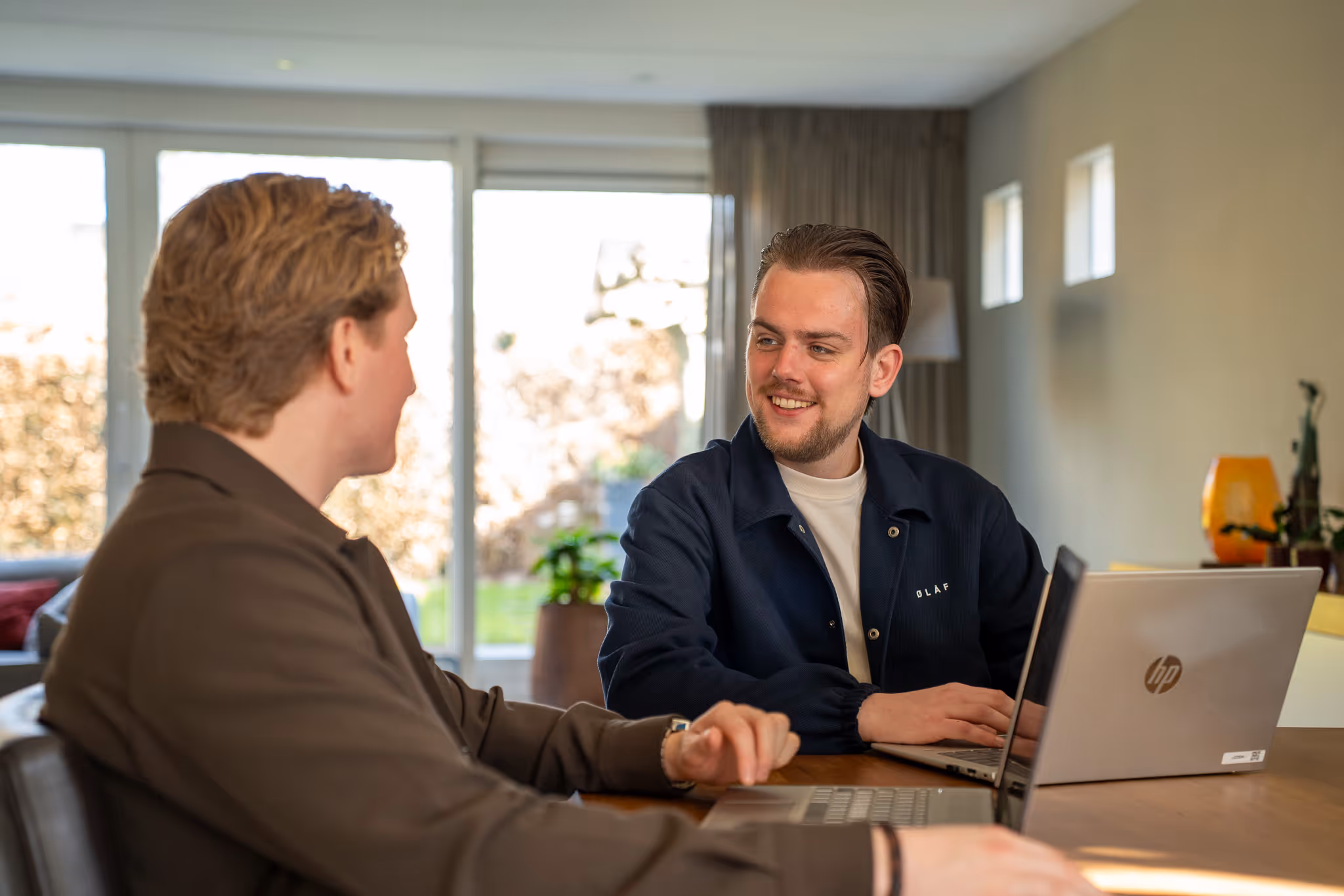 Timo en Stan van SENT Marketing in gesprek aan een tafel met laptops in een lichte kantoorruimte, wat de persoonlijke aanpak en korte lijnen symboliseert.