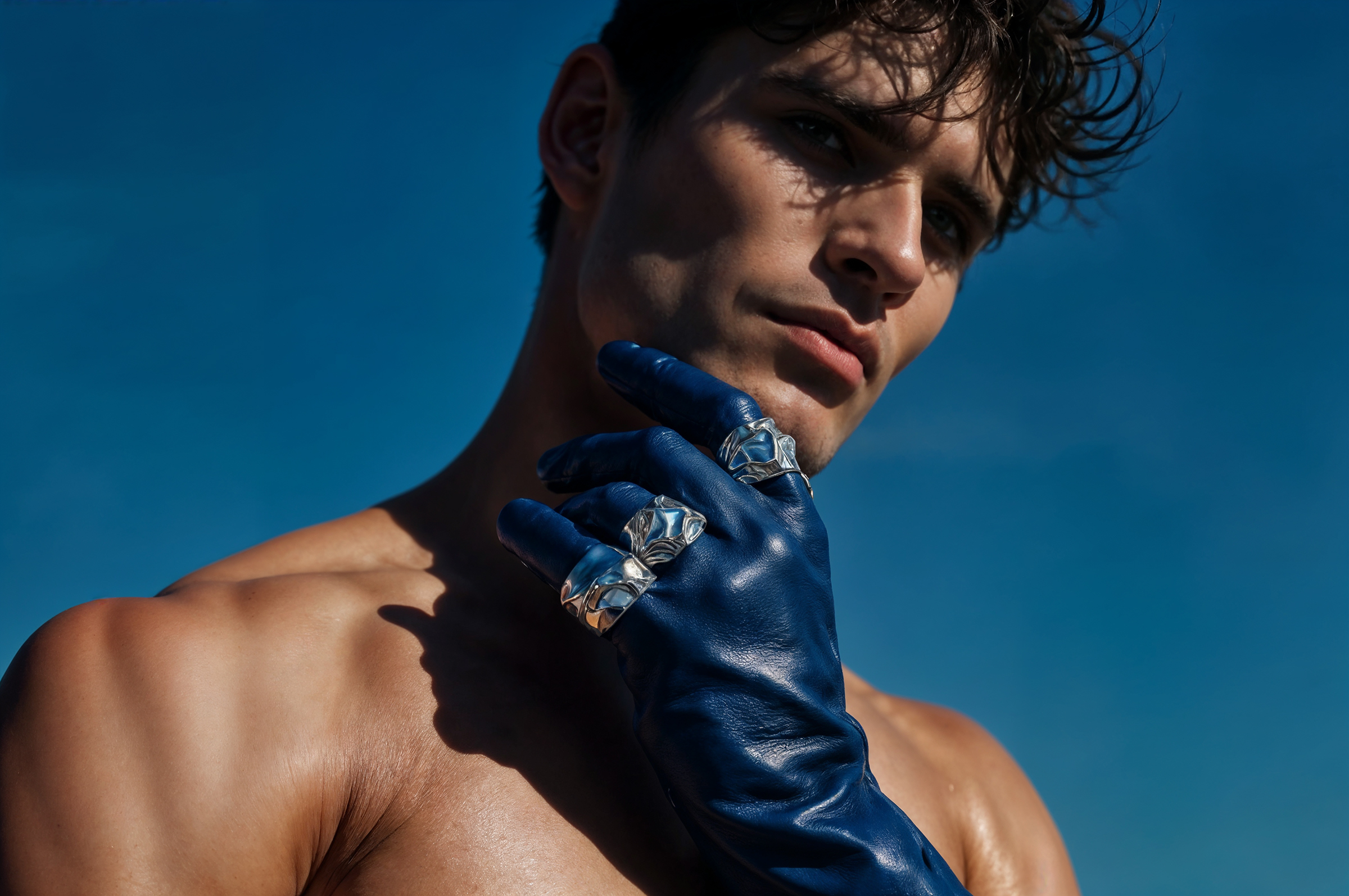 A shirtless man wearing blue leather gloves.