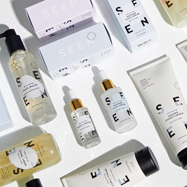SEEN – flat lay of white and neutral haircare and skincare products arranged on a light background.