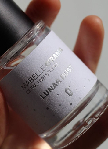 Mabelle O’Rama Olfactive Studio – Lunar Dust 01 perfume bottle held between fingers in soft natural light.