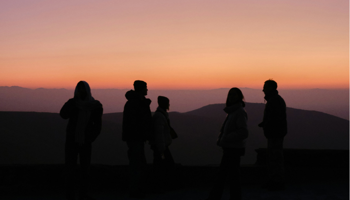 Silhouettes of people standing together at sunset, representing Constellar’s monthly group membership for founders.