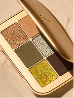 Lisa Eldridge – open gold-toned eyeshadow palette with warm neutral and glitter shades on a beige background.