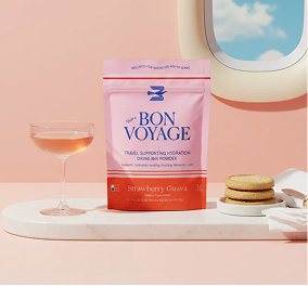Bon Voyage – Strawberry Guava hydration drink mix pouch styled with cocktail glass and biscuits on a pastel set.