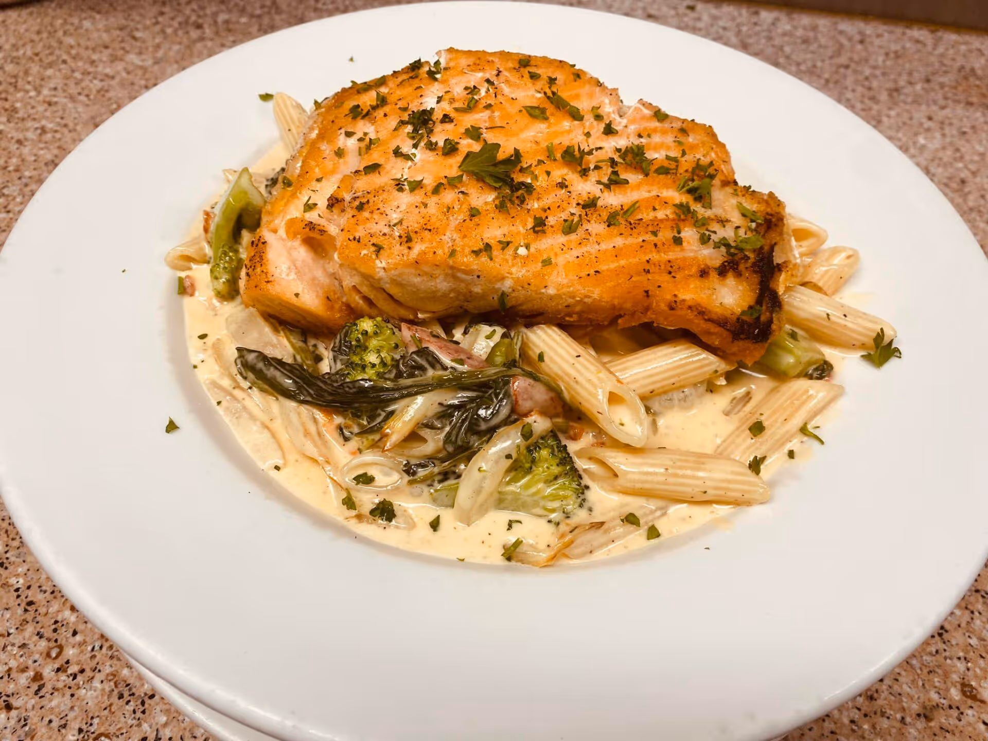 A white plate with a piece of fish and vegetables on it.