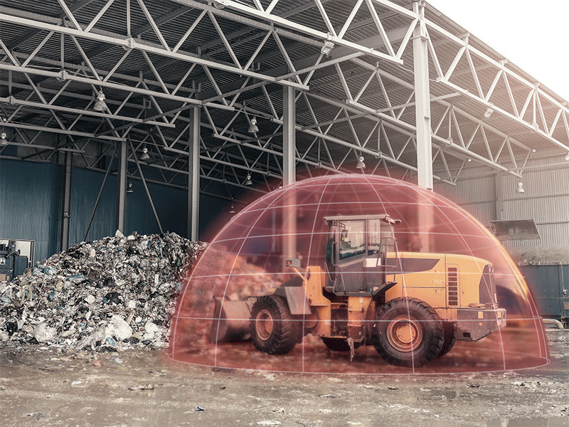 A wheel loader with a detection bubble around it, shovelling waste at a recycling facility
