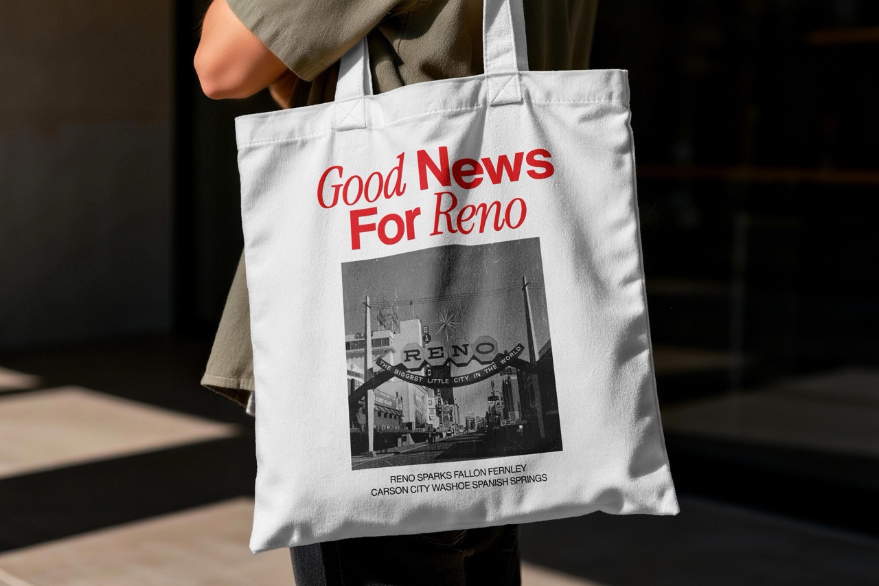 White tote bag with red text 'Good News For Reno' above a black and white photo of the Reno arch and city street.
