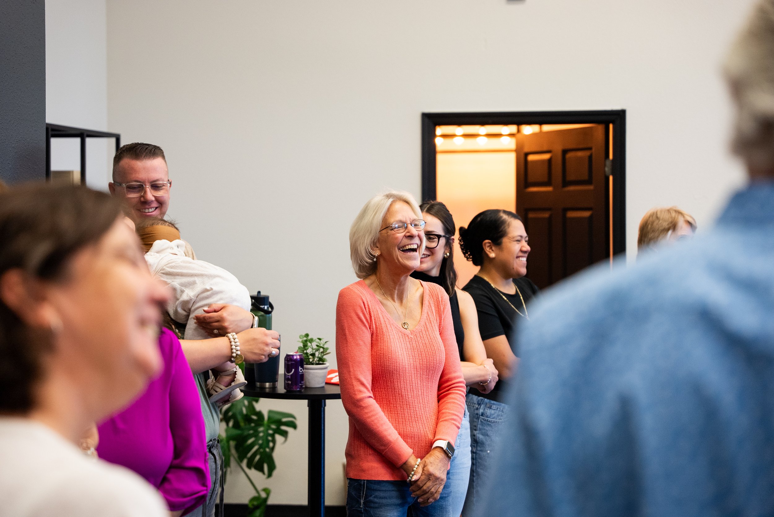 Group of diverse people smiling and laughing together at an indoor social gathering.