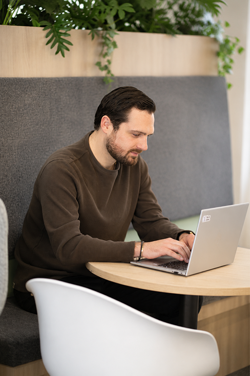 Man with dark hair and beard using a laptop at Nave Bank.