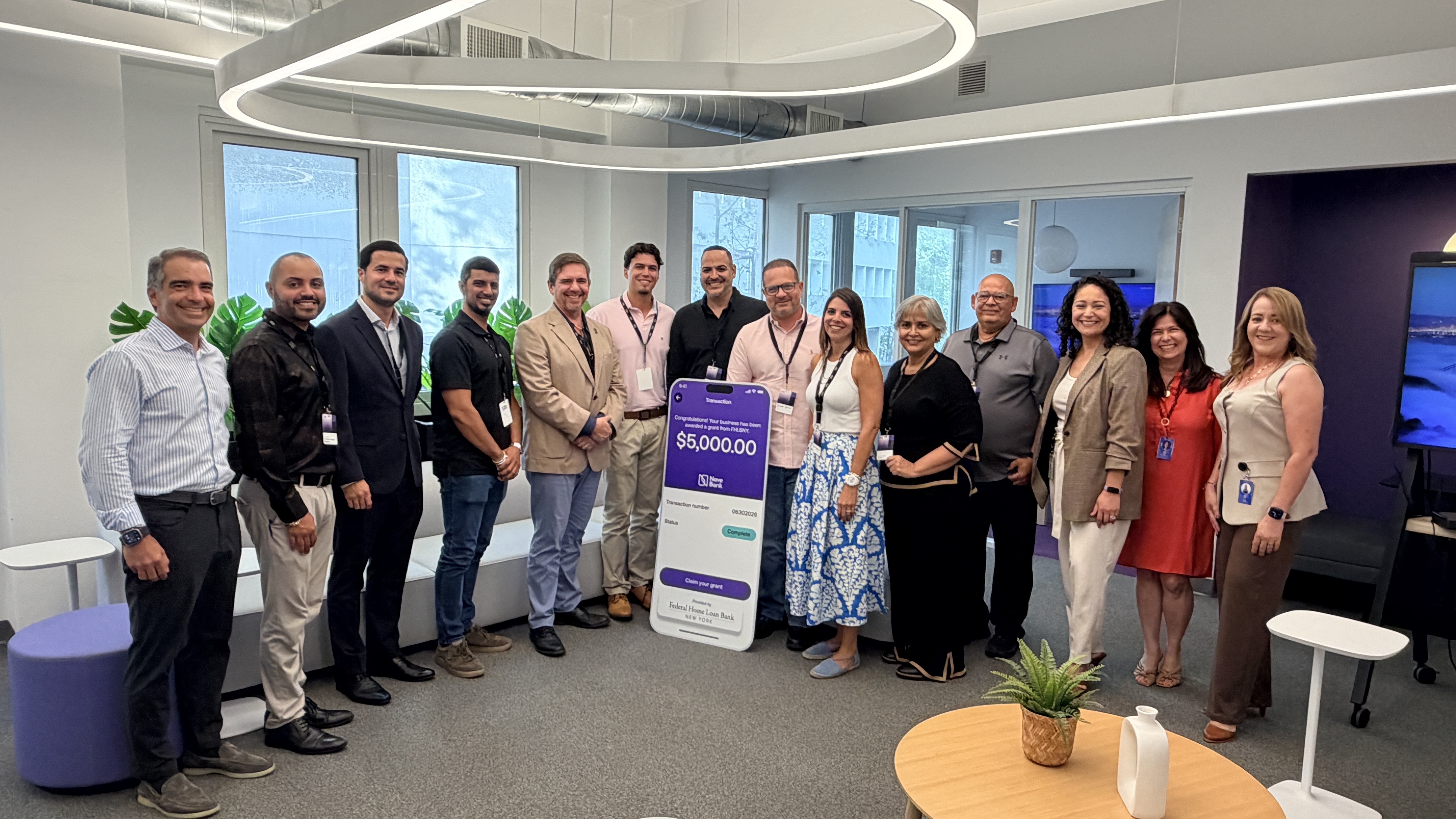 Grupo de personas posando con una pantalla que muestra una subvención de $5,000 en Nave Bank. 