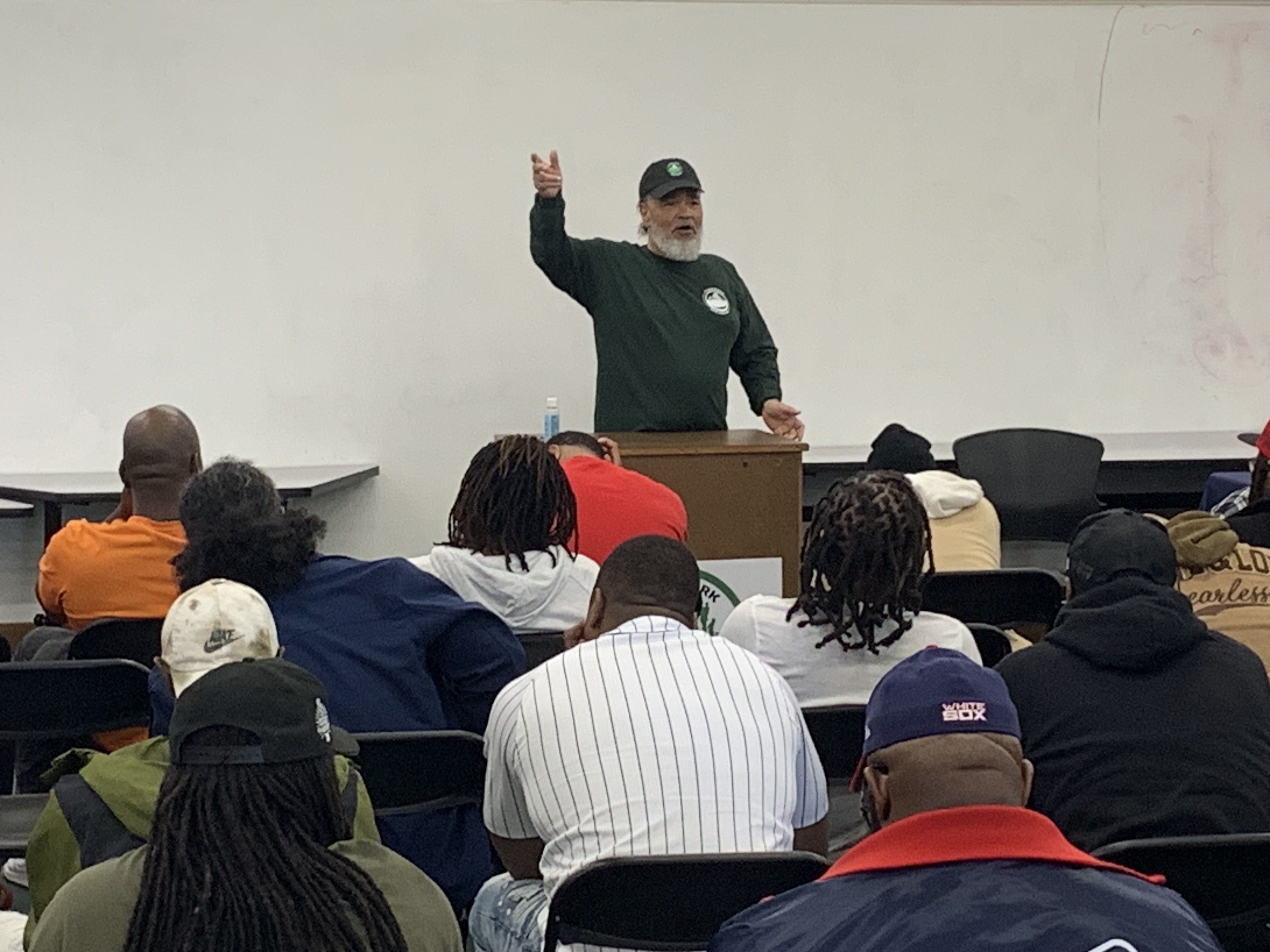 Photo of a man speaking behind a podium in an office conference room. 