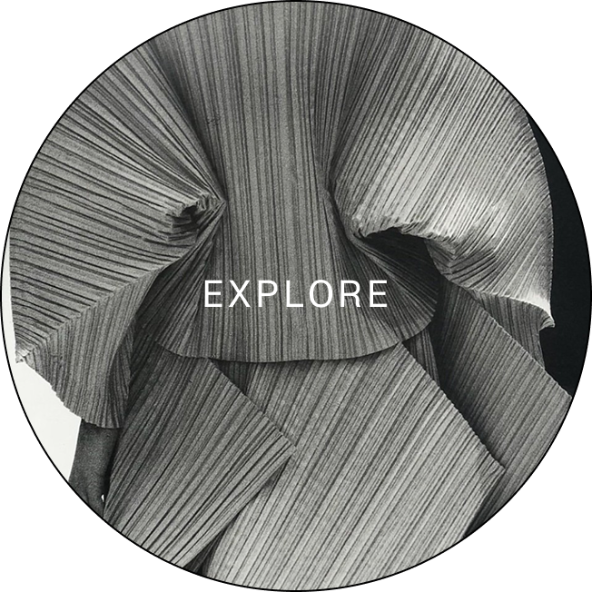 Black and white close-up of pleated fabric folds with the word 'EXPLORE' in white text centered on the image.