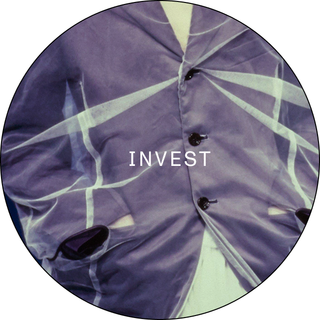 Close-up of a purple jacket with buttons, featuring the word 'INVEST' printed across the front.