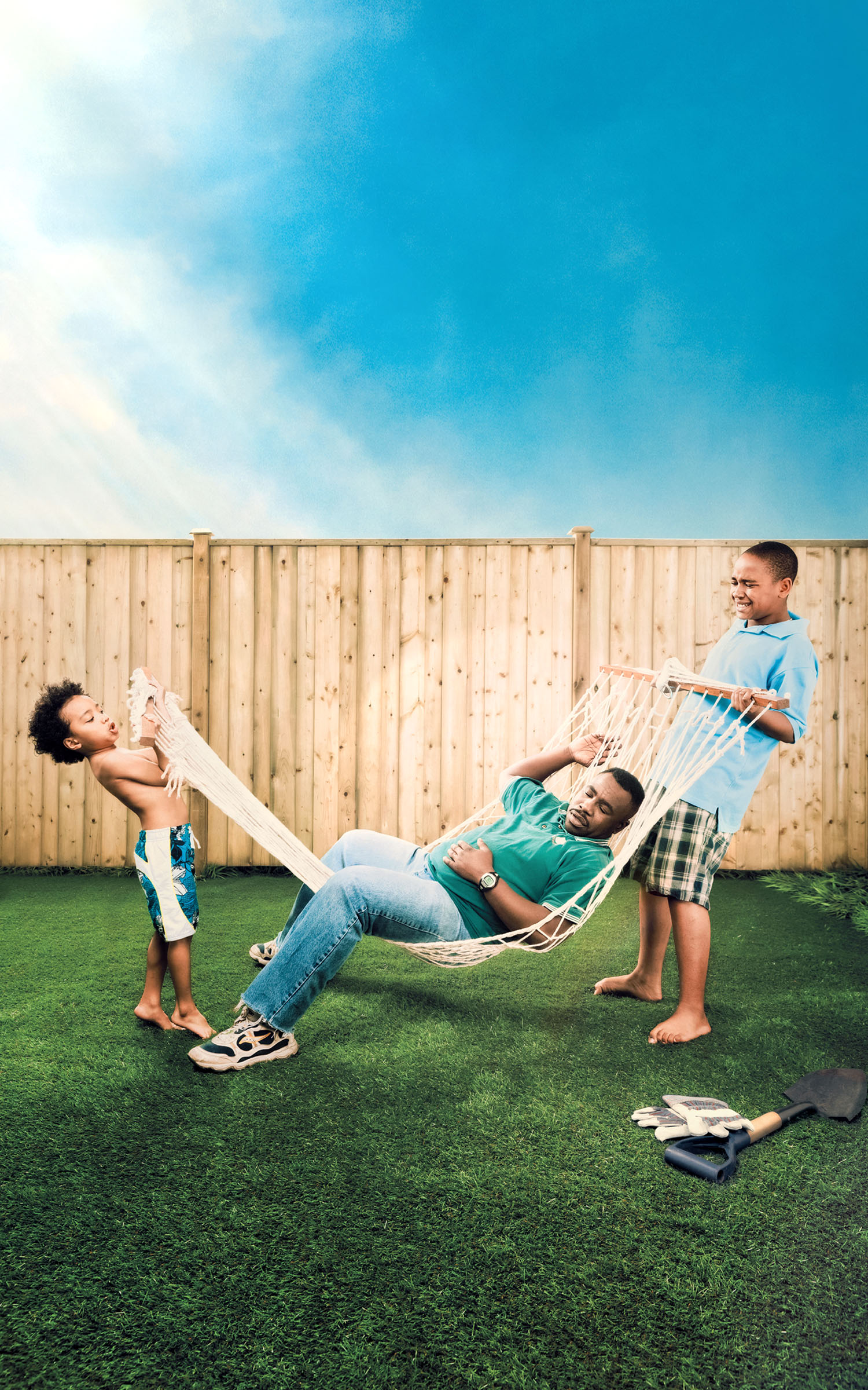 Two boys struggling to hold up their father in a hammock in a backyard without trees, Ontario Power Generation campaign.