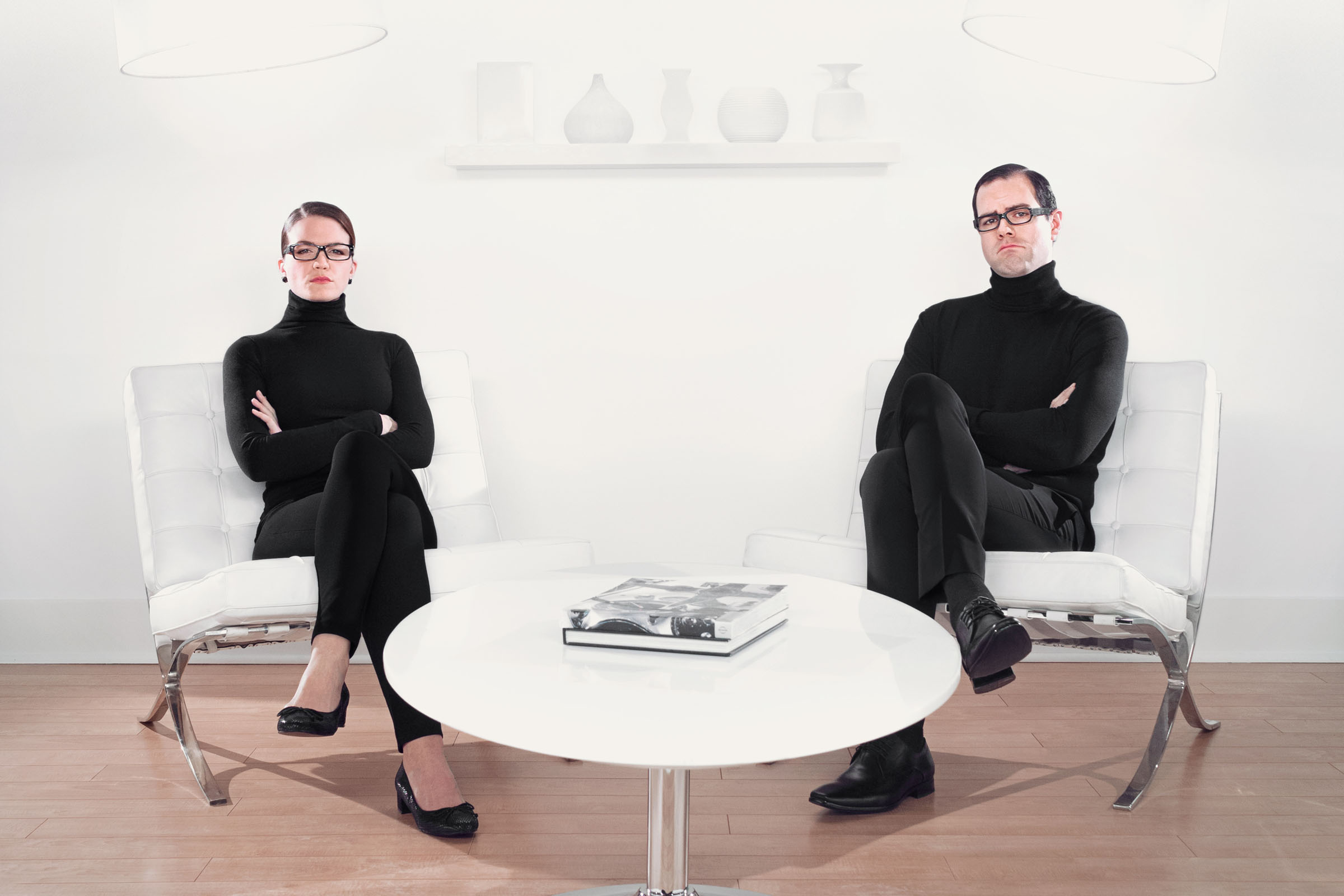 Designer couple in black turtlenecks seated in minimalist living room interior, Zoocasa campaign.