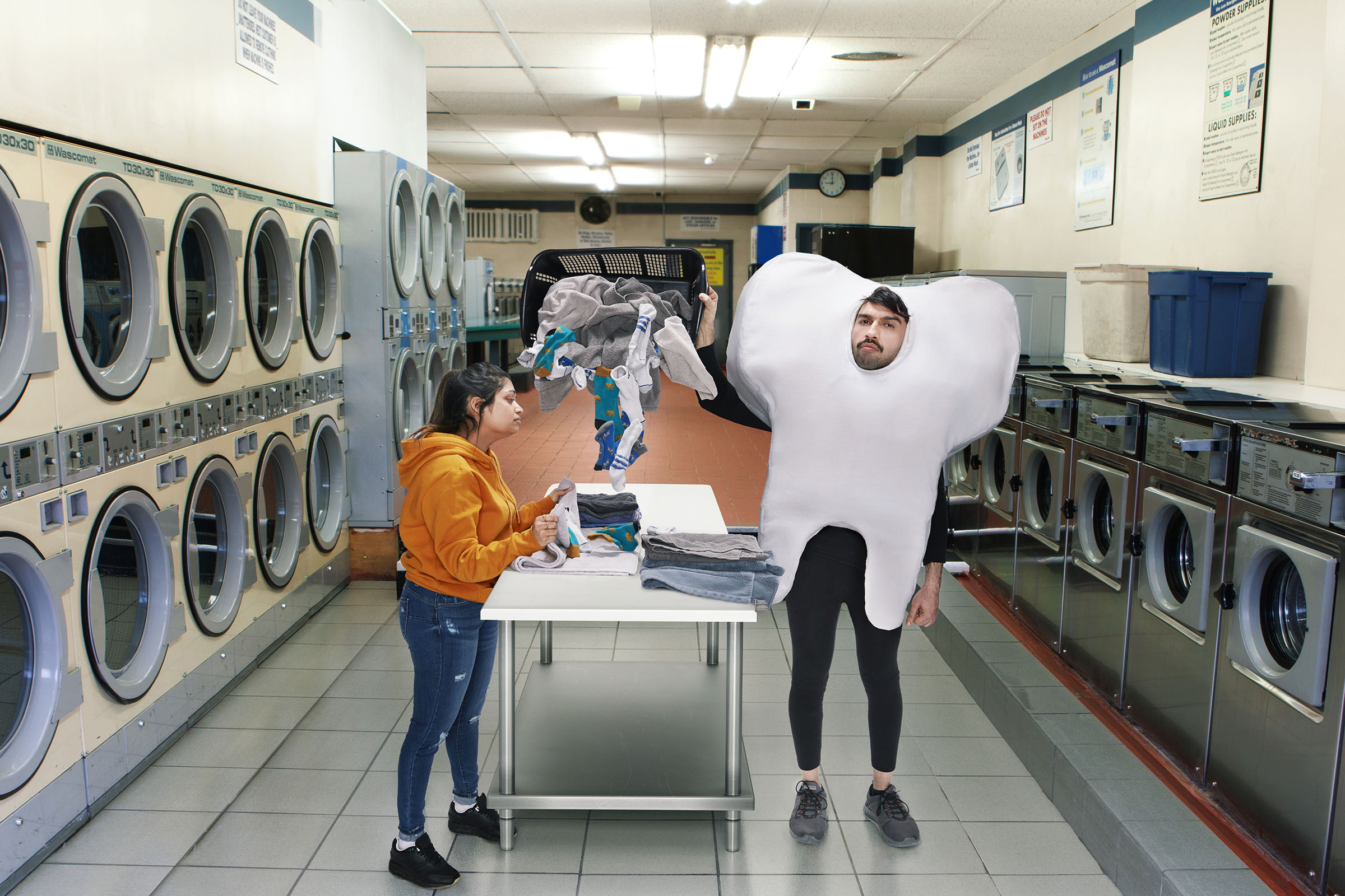 Person in tooth costume interrupting woman folding laundry in laundromat, Ontario Dental Association campaign