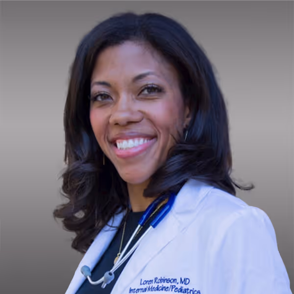 Smiling female doctor with dark hair wearing a white coat and stethoscope.