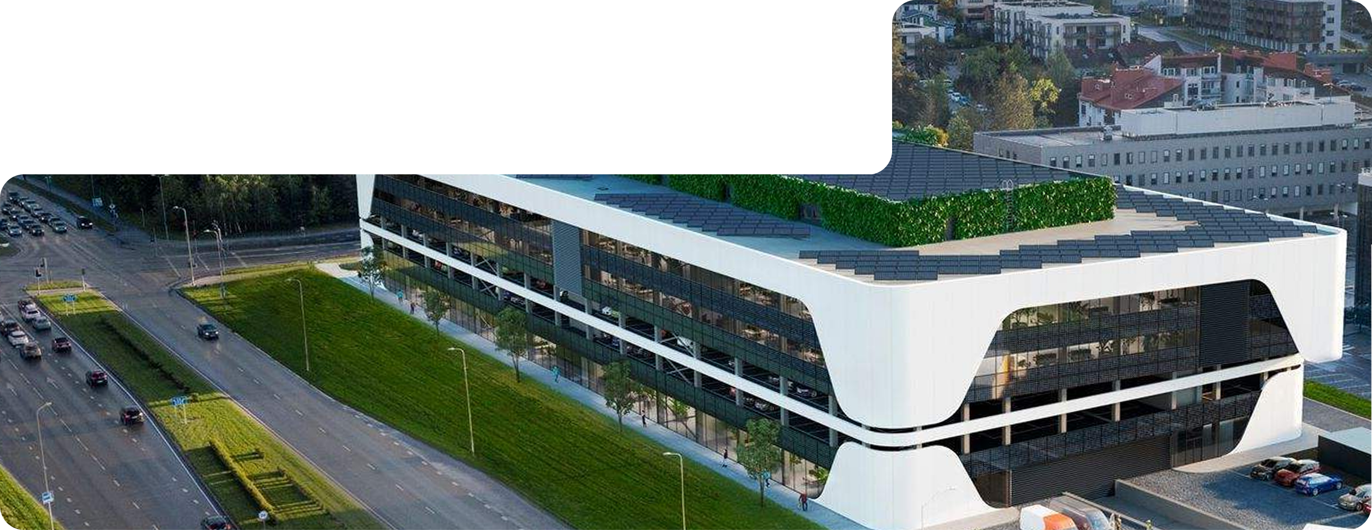 Modern office building with curved white exterior and rooftop greenery beside a busy road.