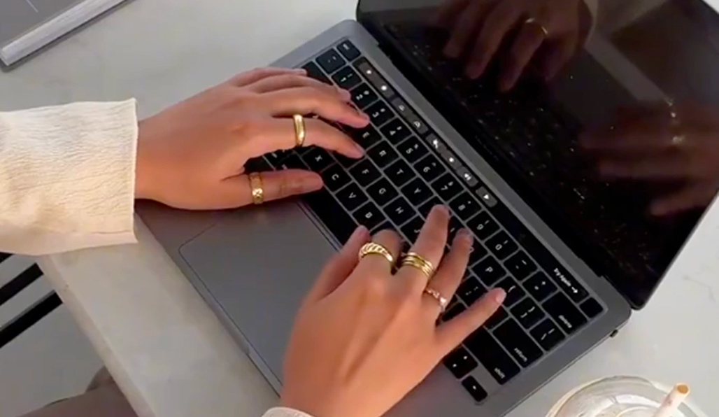 A person is holding a phone in a hand above apple macbook