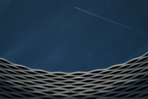 a plane flying in the sky over a building