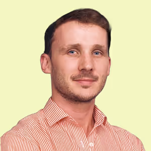 Portrait d'un homme aux cheveux courts et barbe légère portant une chemise rayée rouge et blanche, sur fond jaune clair.