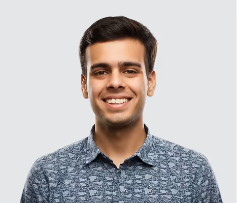 Jeune homme souriant portant une chemise bleu à motifs devant un fond gris clair.