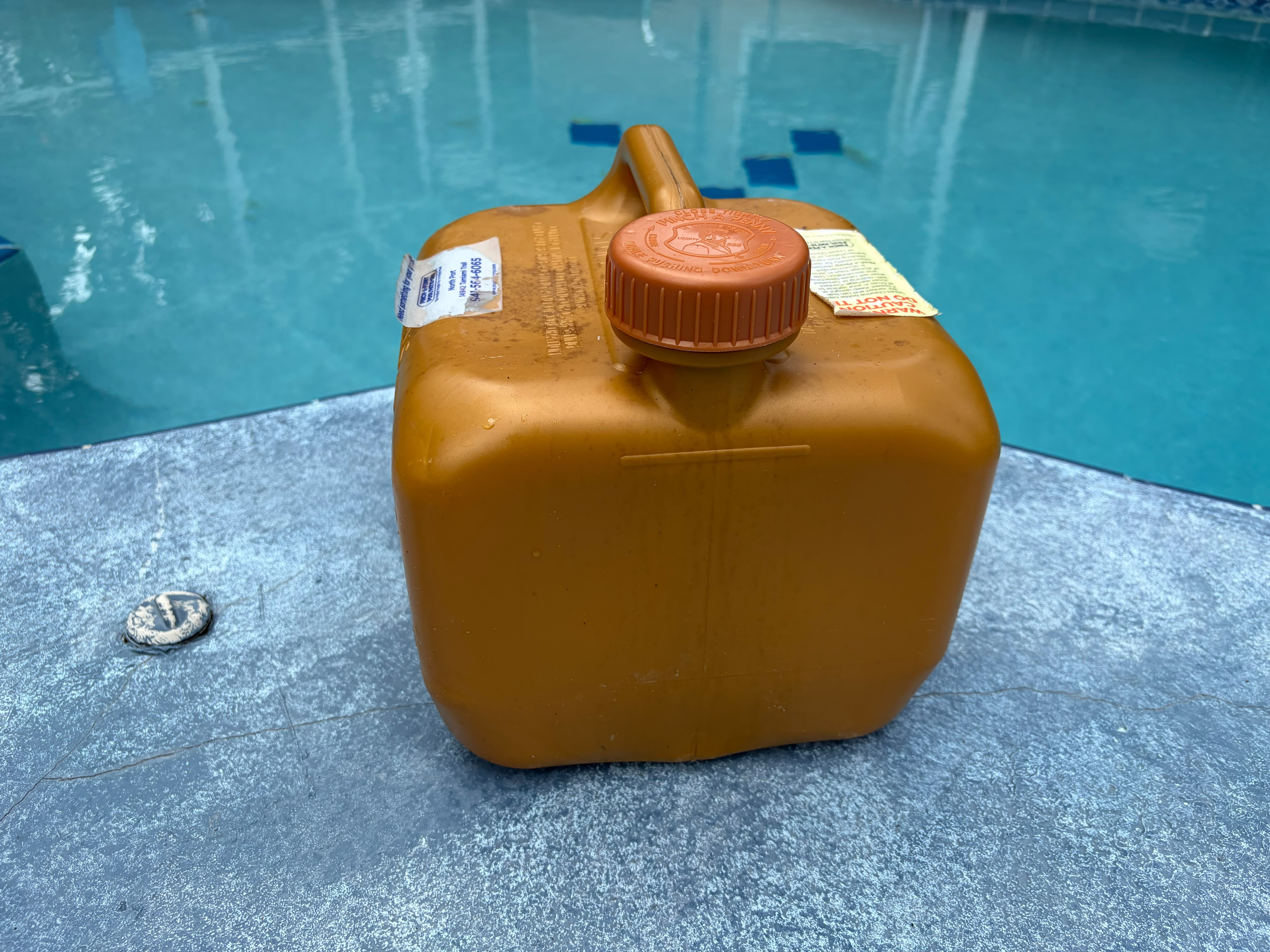 Liquid chlorine jug beside a residential swimming pool in North Port, Florida.