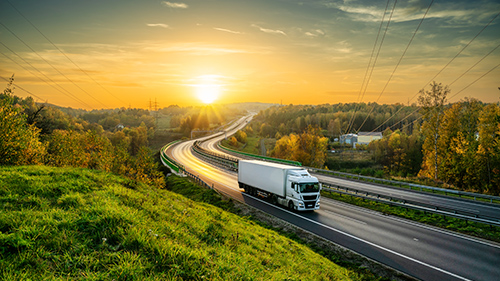 Freight trucking driving on road at sunset