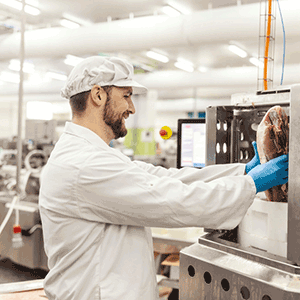 Male worker processing livestock meat at a plant