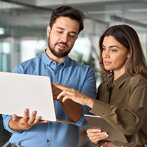 Two workers standing looking at a laptop