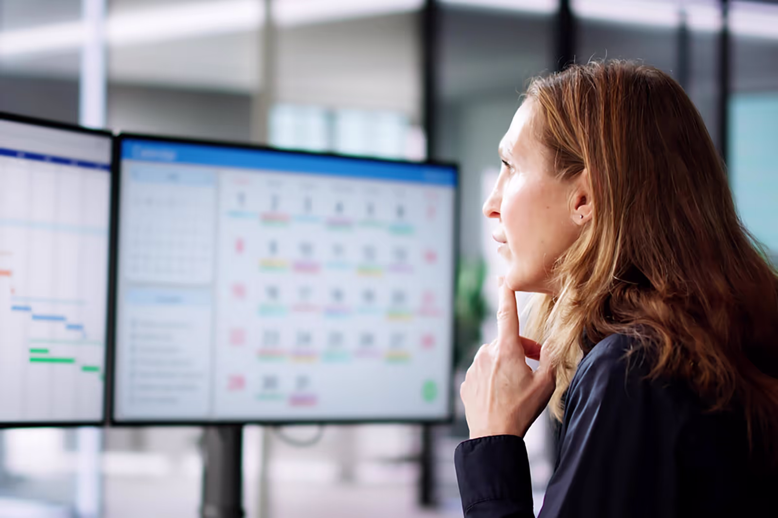 Female worker looking at two computer screens