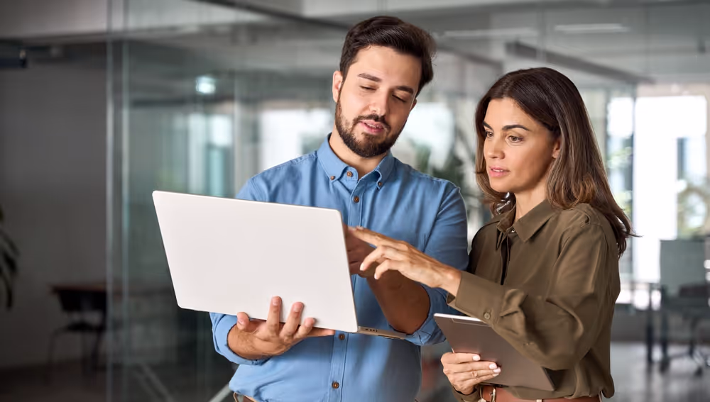 Two workers standing looking at a laptop