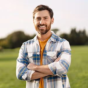 Man stood in a field with his arms crossed