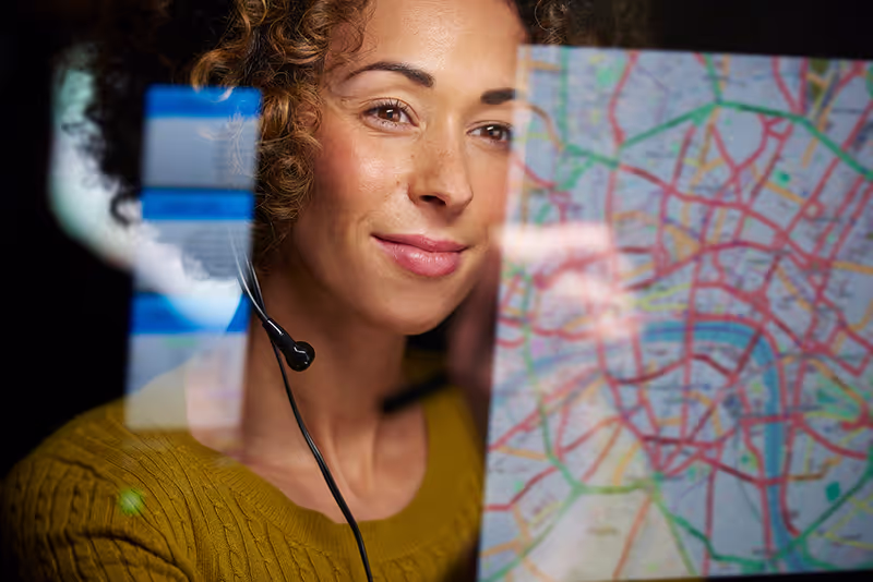 Female dispatcher with headset looking at map on a computer 