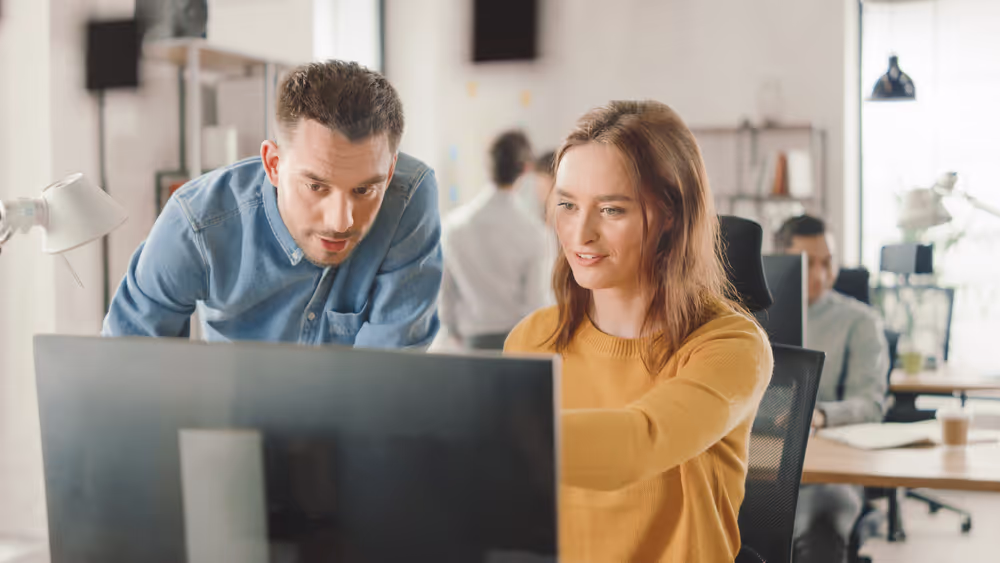 Female and male workers looking at computer together