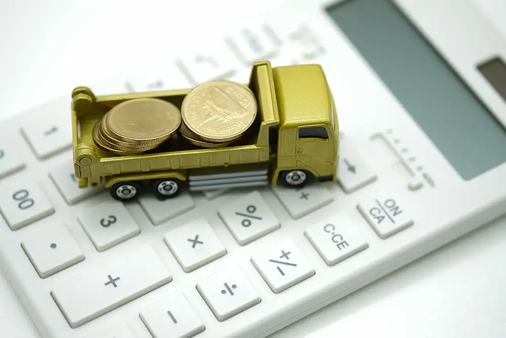 Small toy truck carrying coins sat on a calculator