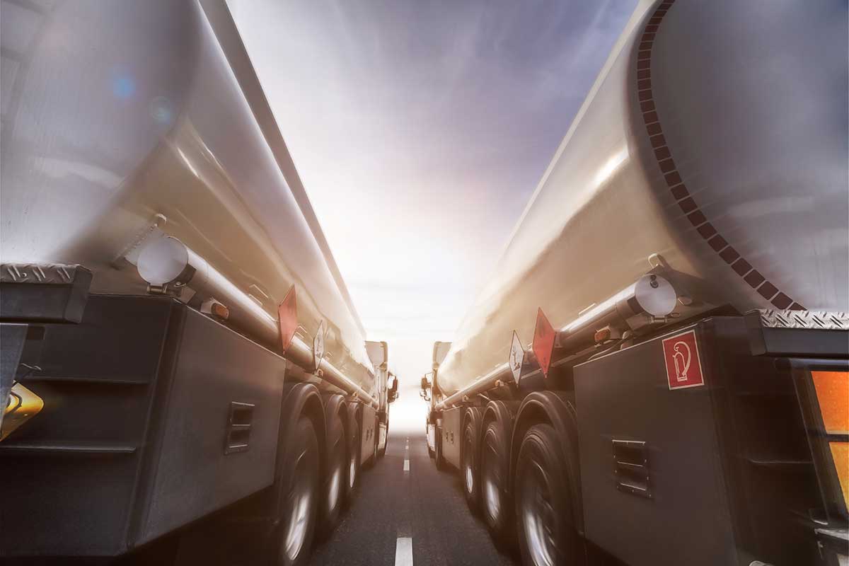 Two tanker trucks driving side-by-side on the highway