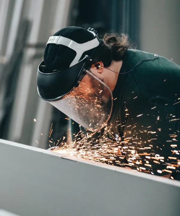 Worker with shield grinding metal