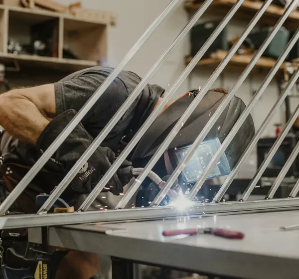 Welder leaning into work on angled metal project
