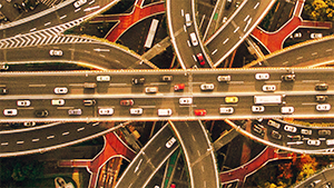 Aerial view of a busy highway interchange with multiple overpasses and several cars traveling in both directions.